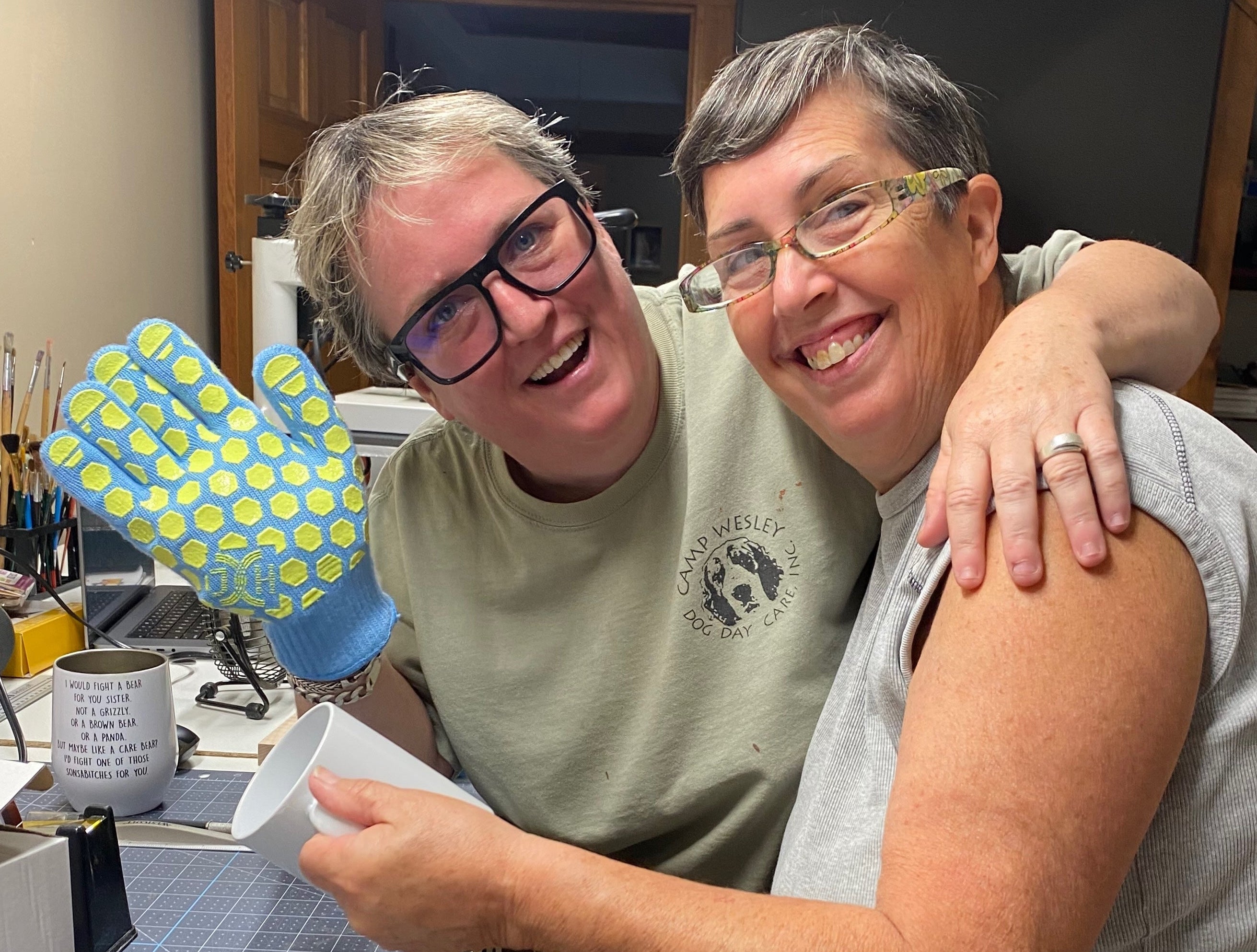 Two people in a kitchen holding a container, with one person wearing glasses and a green shirt.
